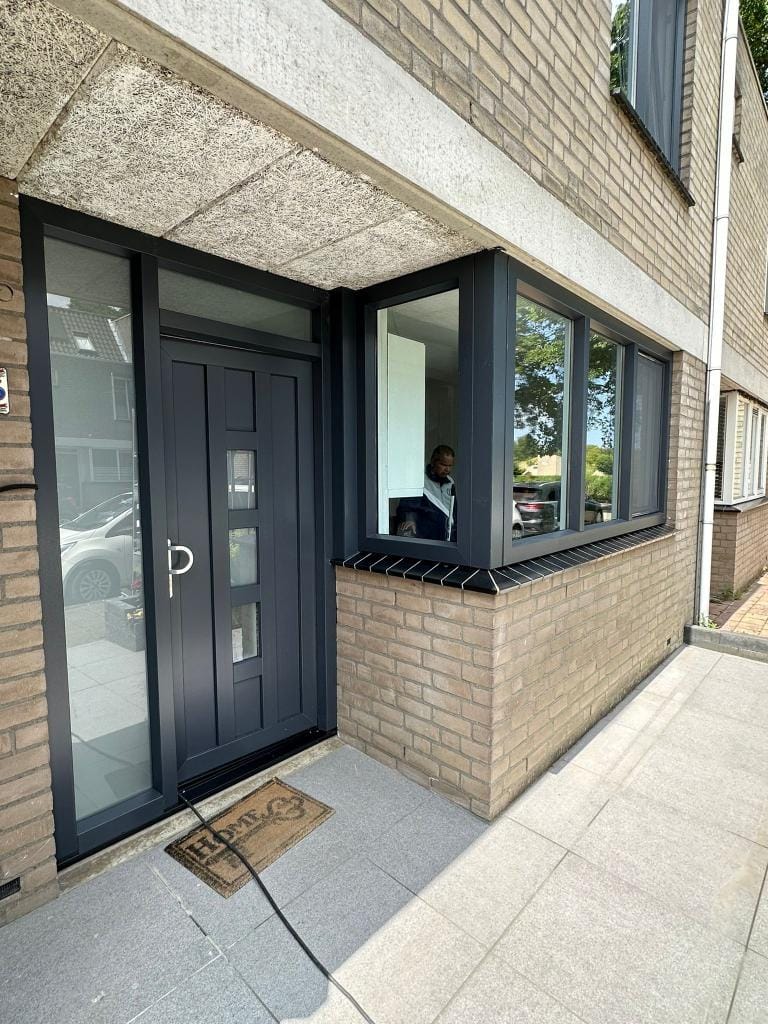 Antraciet kunststof voordeur met zijraam en moderne erker — recent project van Duurkracht Kozijnen