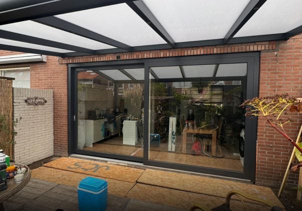 Brede schuifpui met antraciet kunststof profielen — uitzicht op achtertuin